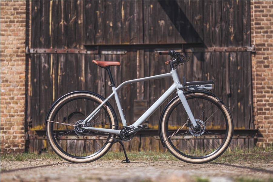 Das Fahrrad Schindelhauer Emil in Farbe mineralgrau ist in einem Hof abgestellt