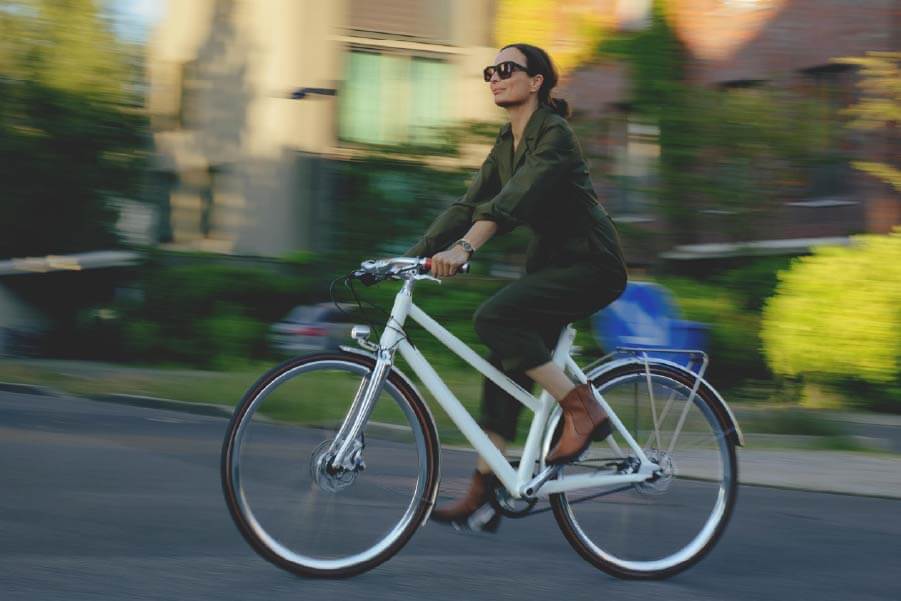 Eine Frau fährt mit Schindelhauer Frieda in Farbe sahneweiß durch die Stadt