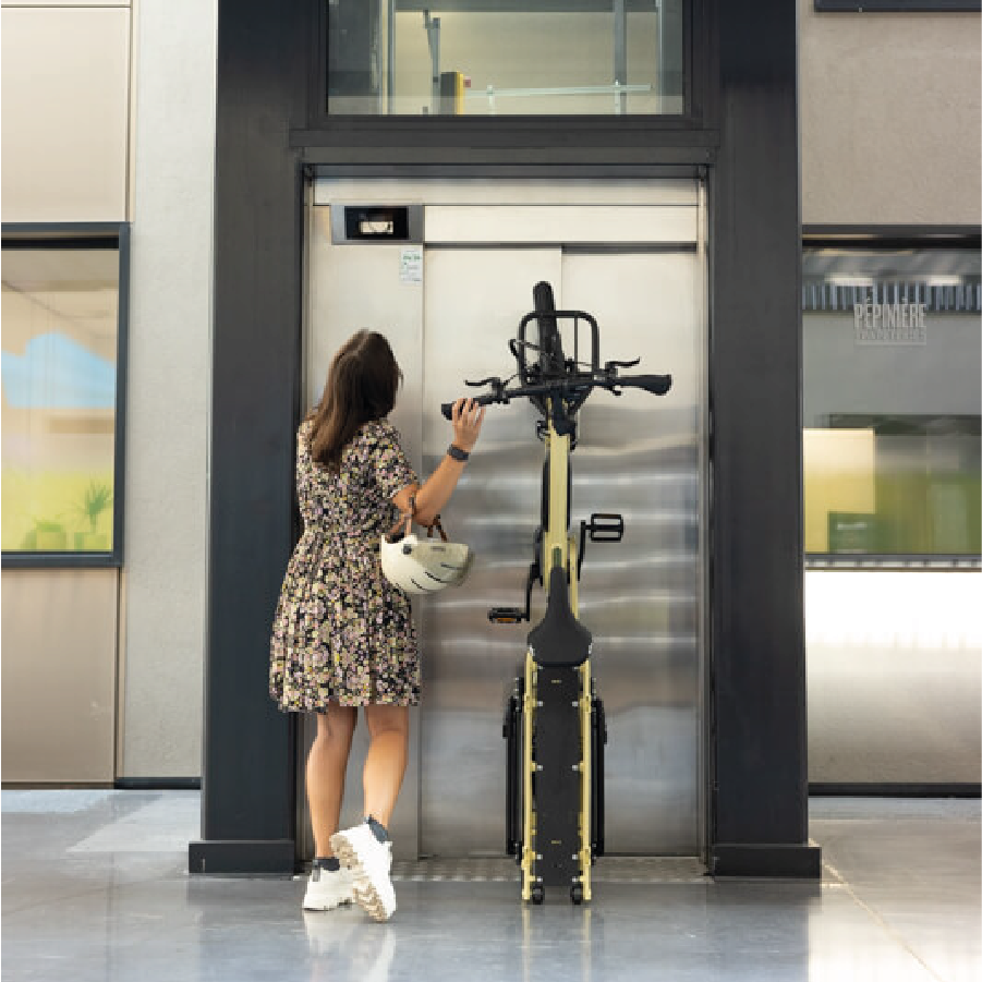 Frau hebt Yuba FastRack in Farbe latte auf einem Rad hoch.